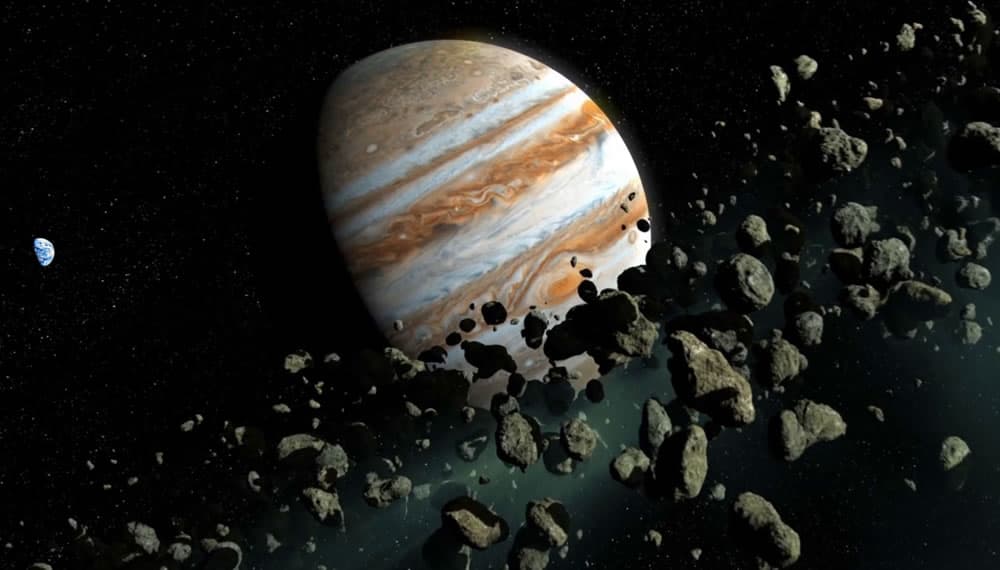 Ilustração 3D mostrando o gigante planeta Júpiter à direita, com sua gravidade atraindo um denso cinturão de asteroides em primeiro plano. Ao fundo, à esquerda, o planeta Terra aparece pequeno e azul, seguro dos detritos espaciais.