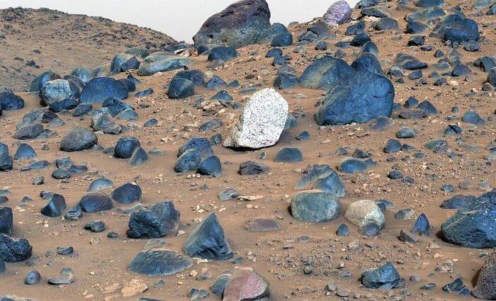 Rochas brancas de caulinita entre fragmentos escuros na superfície da cratera Jezero, registradas pelo Perseverance em Marte.